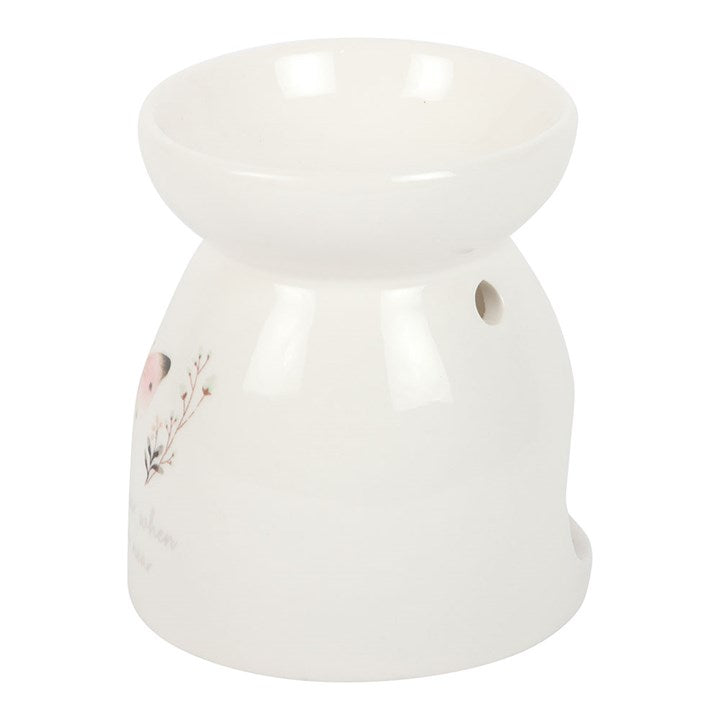 White ceramic oil burner with floral design on a white background