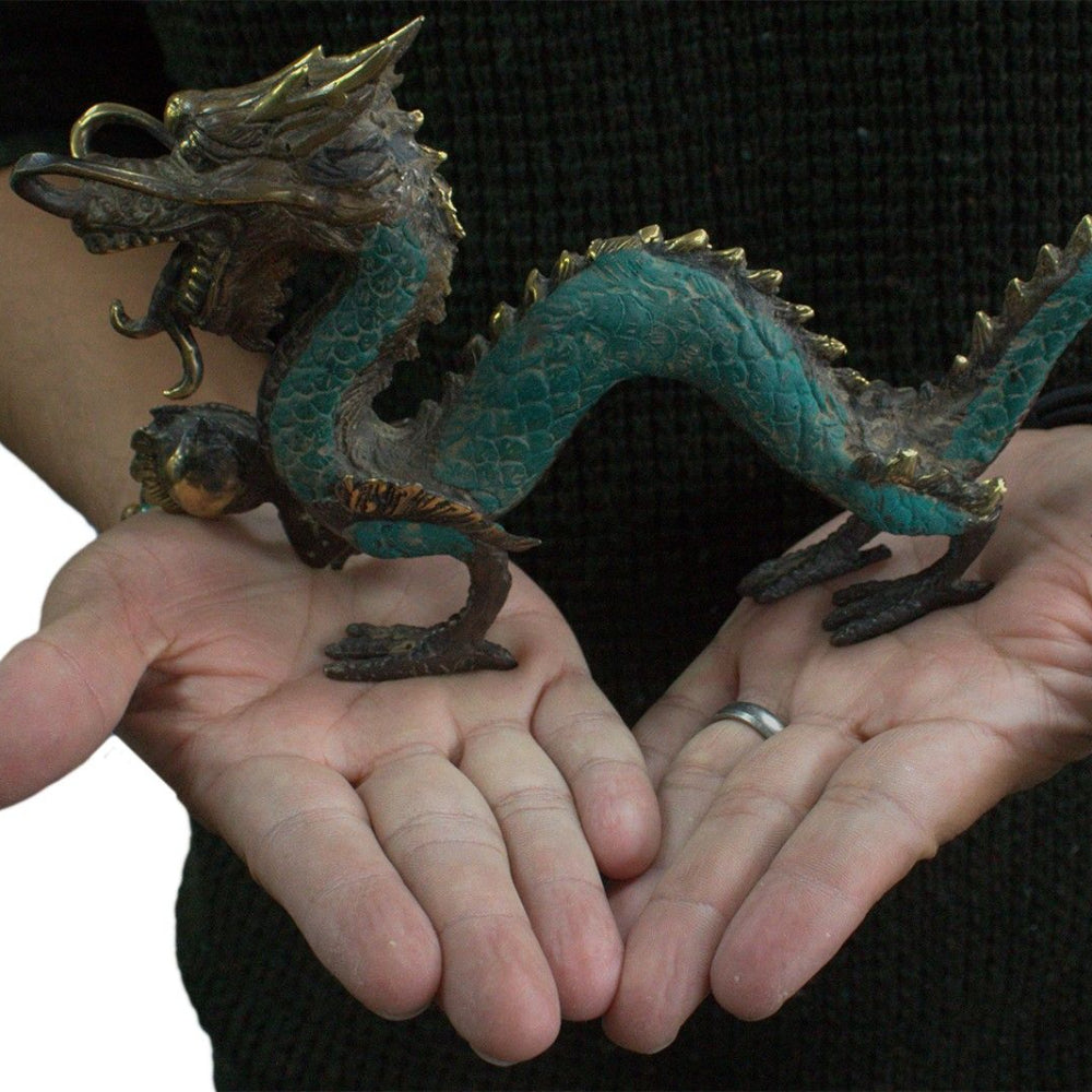 Person holding a small dragon figurine between their palms