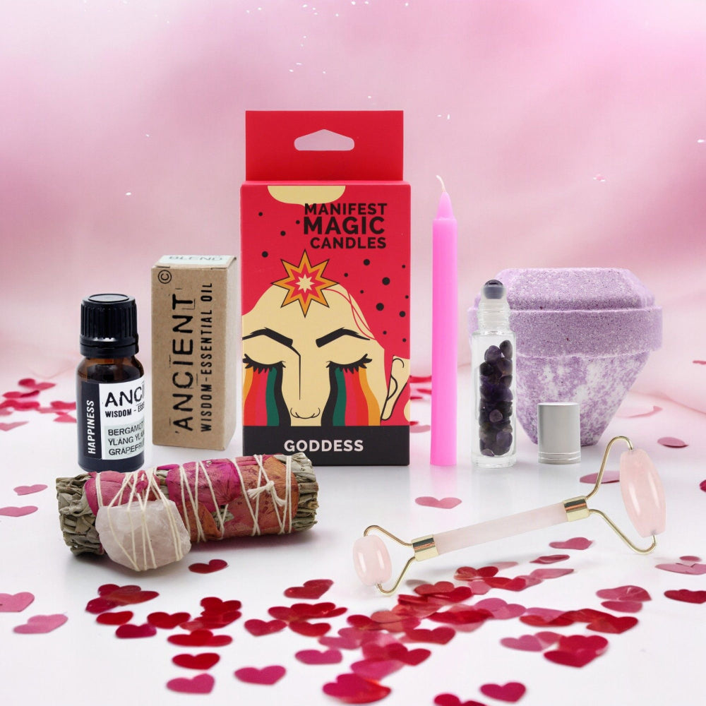 Glowing pink candle, 'Manifest Magic Candles' packaging,  essential oil bottle, and other wellness items on a pink background with heart confetti.