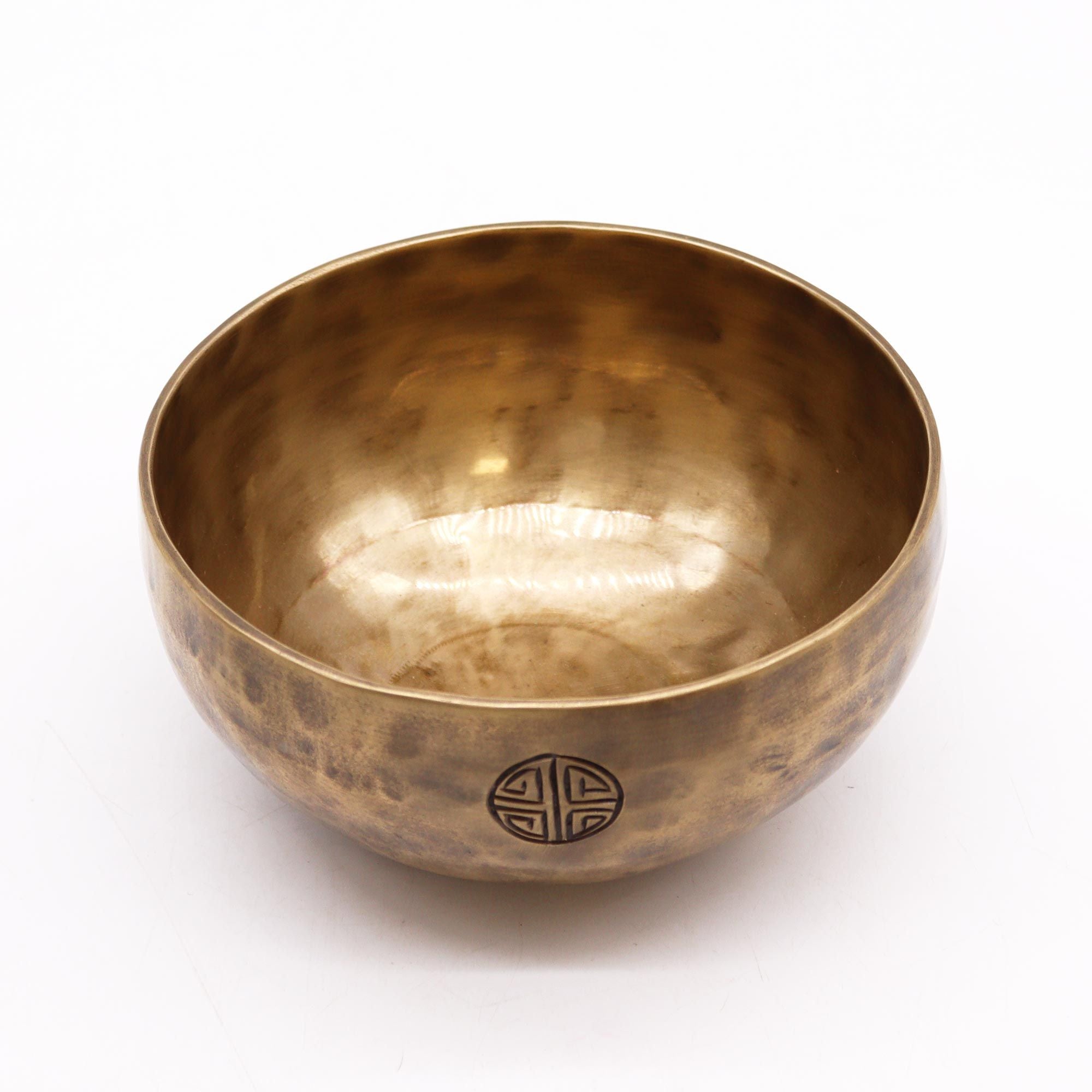 Bronze singing bowl with a decorative emblem on a white background