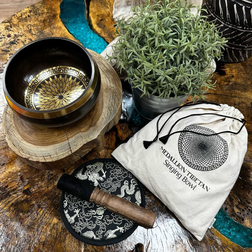 Tibetan singing bowl set with wooden stand, mallet, and pouch on a wooden surface.