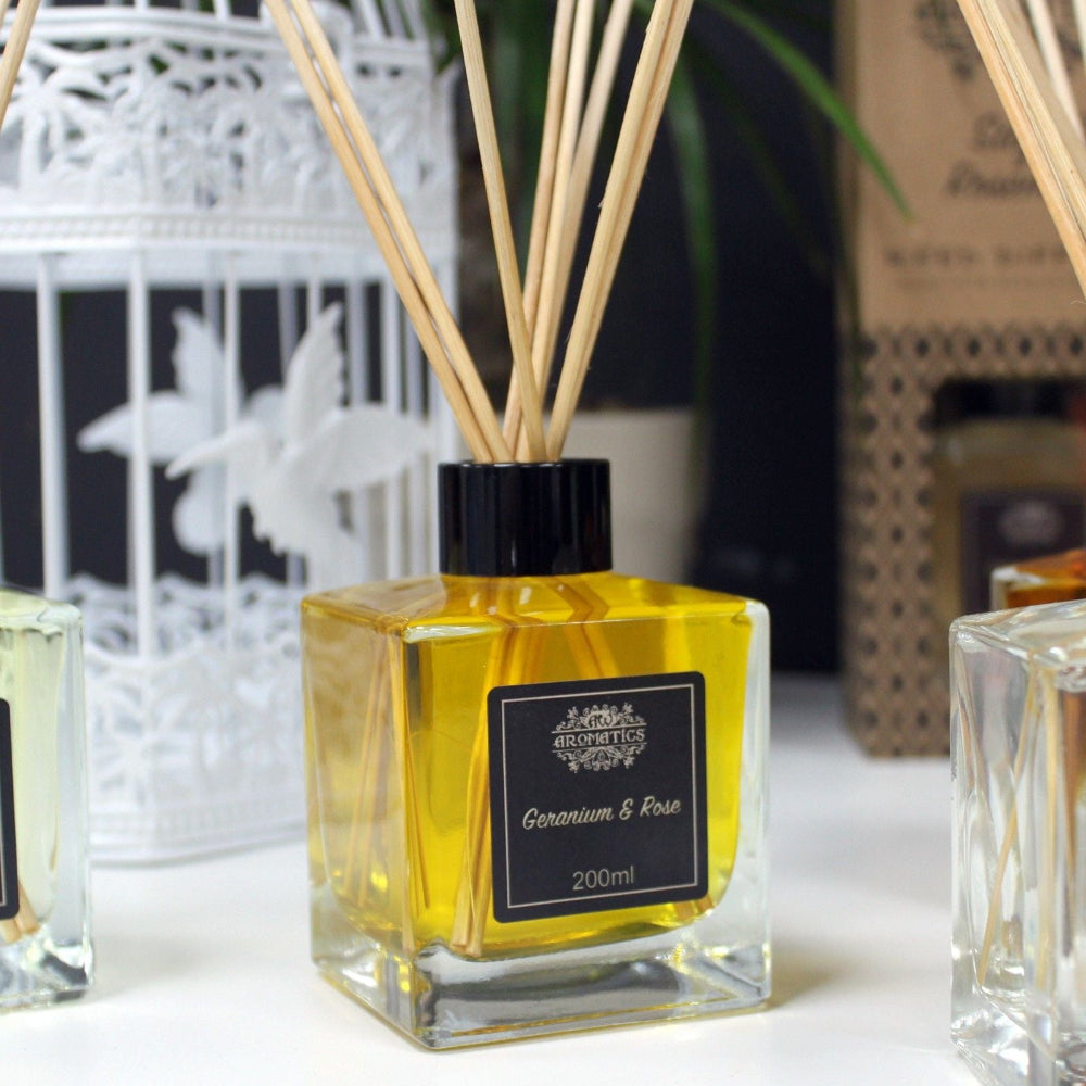 A square glass diffuser bottle with wooden sticks on a white surface.