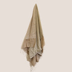 Beige and white striped towel with fringes on a beige background