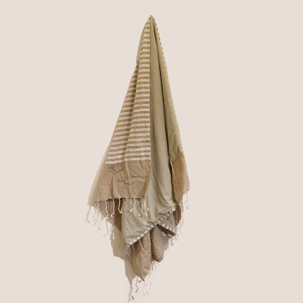 Beige and white striped towel with fringes on a beige background