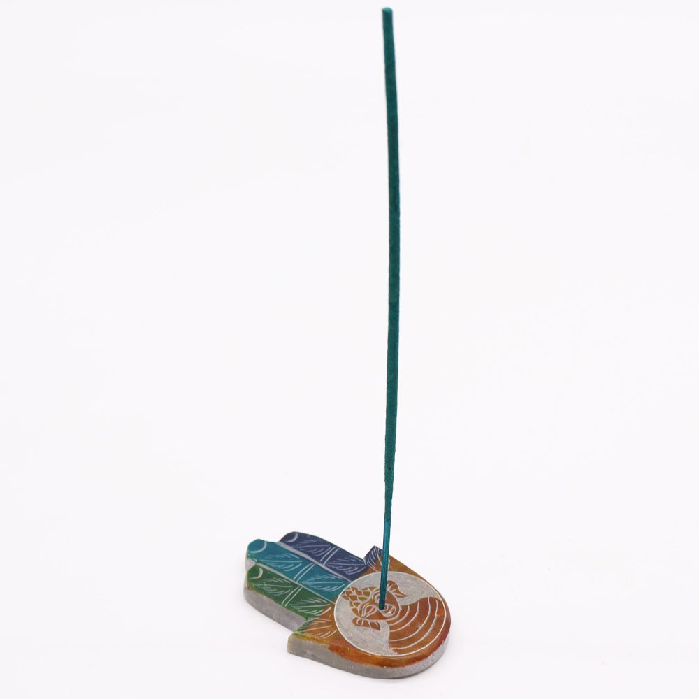 Colorful incense holder with a single green incense stick on a white background