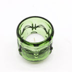 Green glass candle holder with alien face design on a white background