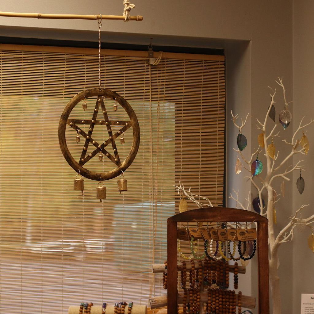 Decorative pentacle wall hanging with beads in a room setting.