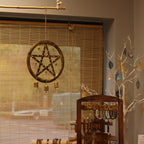 Decorative pentacle wall hanging with beads in a room setting.