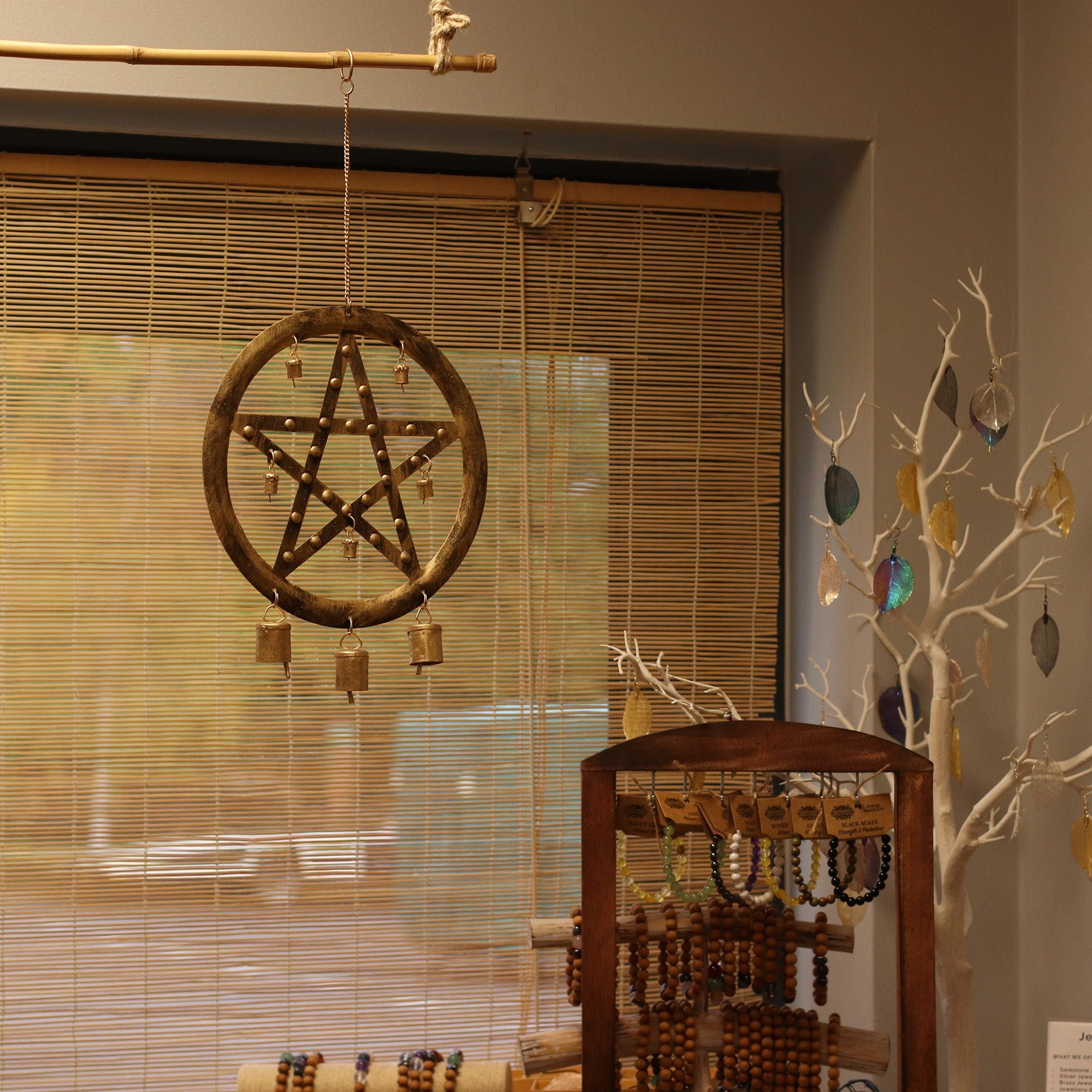 Decorative pentacle wall hanging with beads in a room setting.