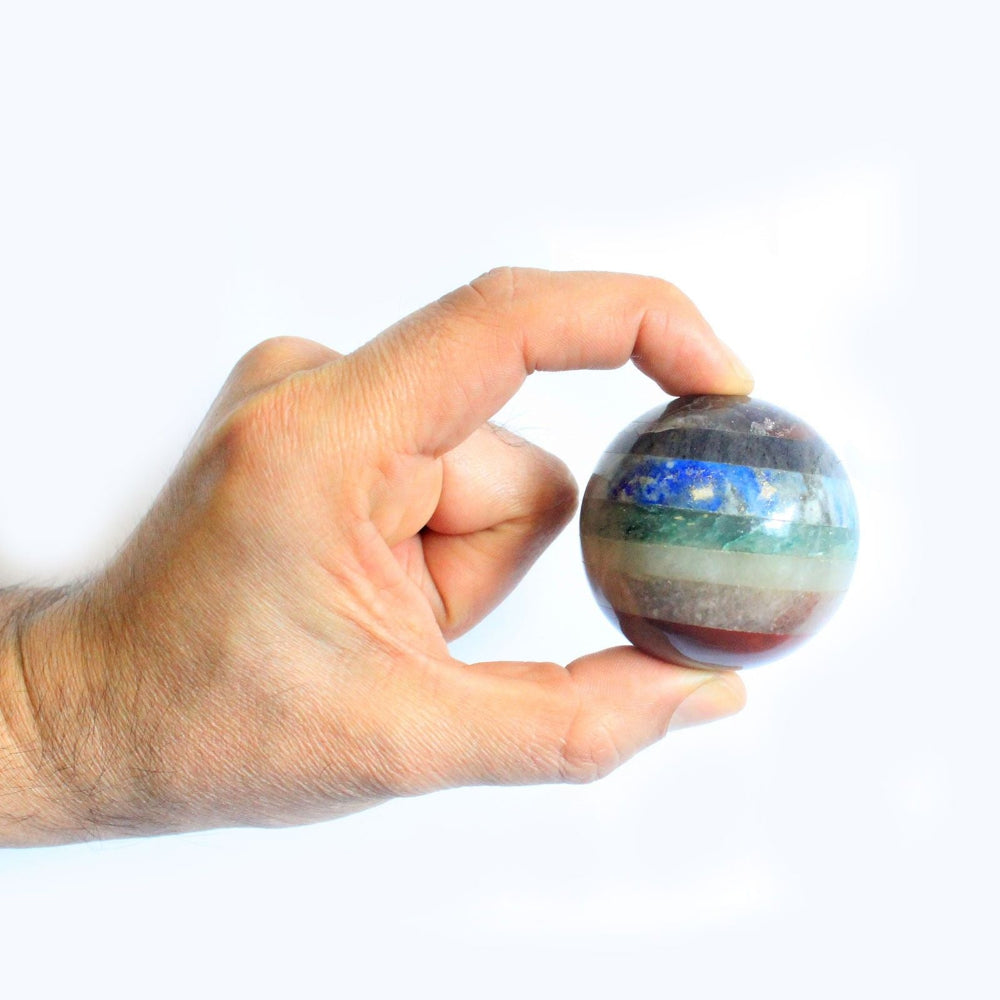 Hand holding a multicolored marbled sphere against a white background