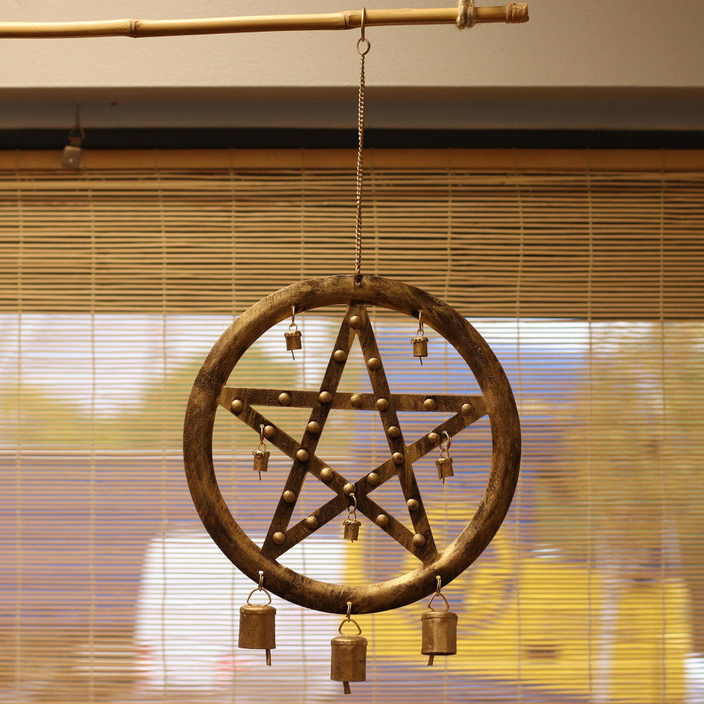 Decorative metal wind chime with star design hanging against a blurred indoor background.