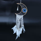 Dreamcatcher with crescent moon design and white feathers on a dark background