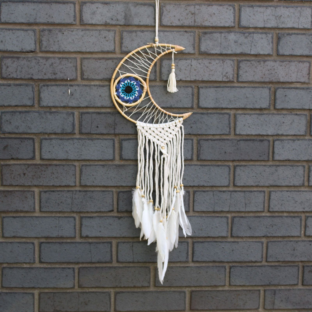 Decorative dreamcatcher with feathers hanging against a brick wall.
