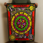 Person holding a colorful tapestry with symbols and text against a plain wall.