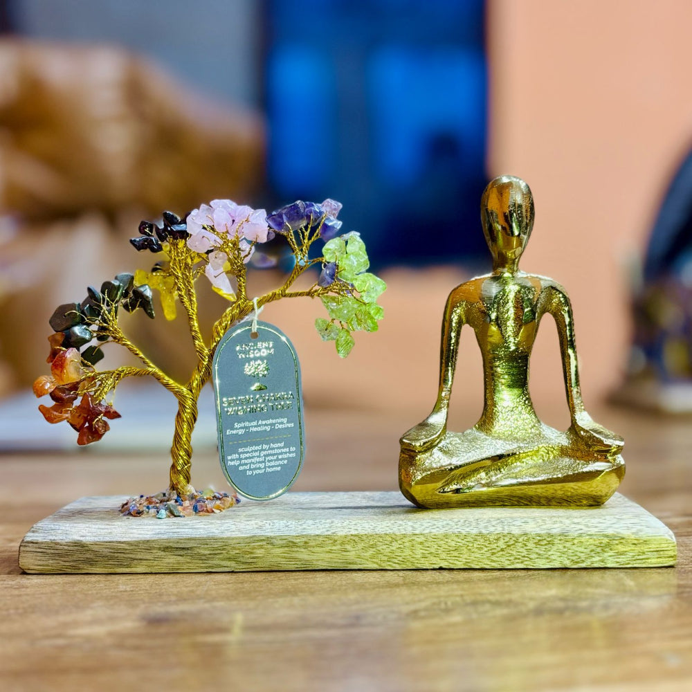 Decorative figurine with a gold-colored seated figure and a tree with colorful stones on a wooden base.