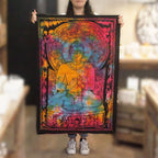 Person holding a colorful tapestry with a Buddha design in a blurred indoor setting