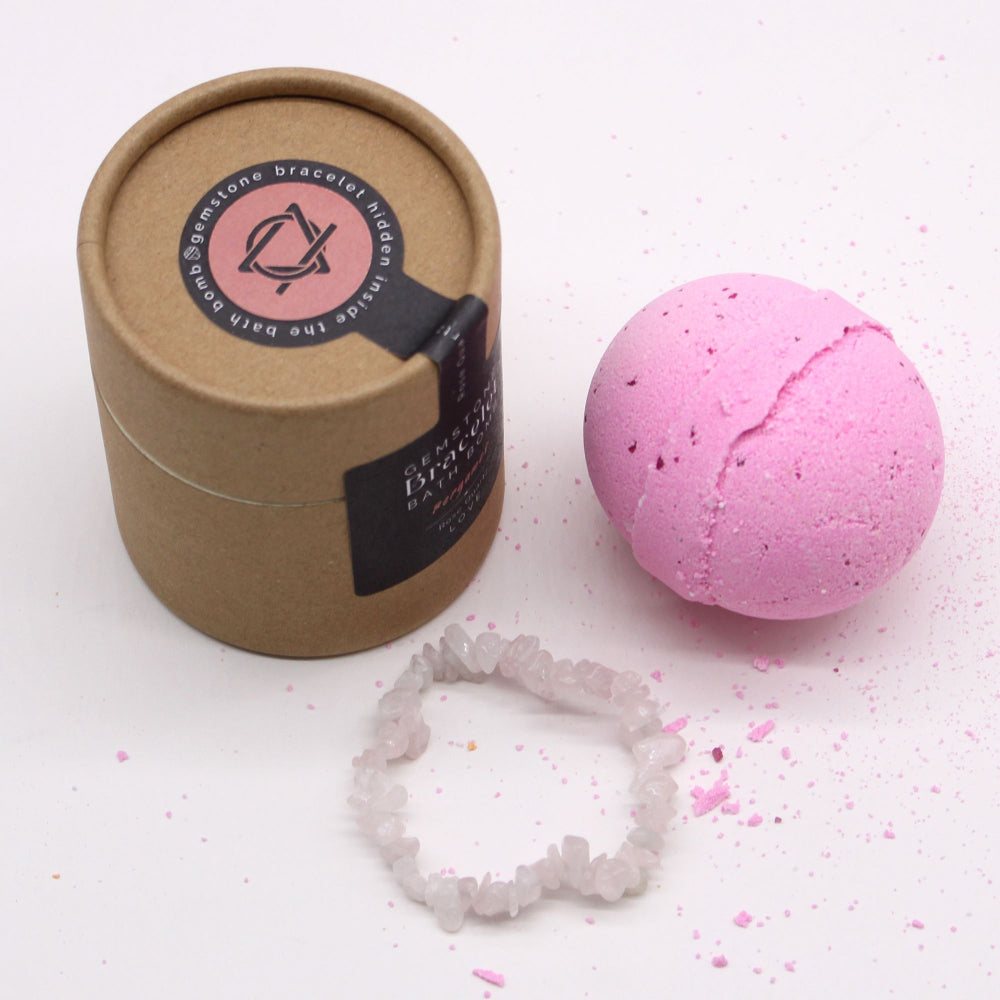 Pink bath bomb next to a brown paper container with a brand label on a white background