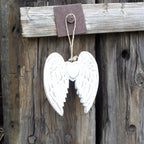 White angel wings hanging on a rustic wooden background