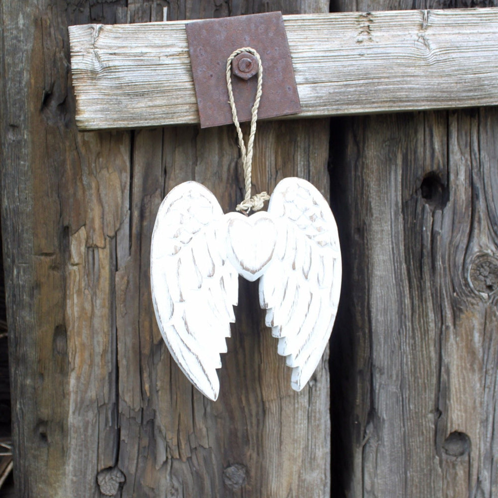 White angel wings hanging on a rustic wooden background