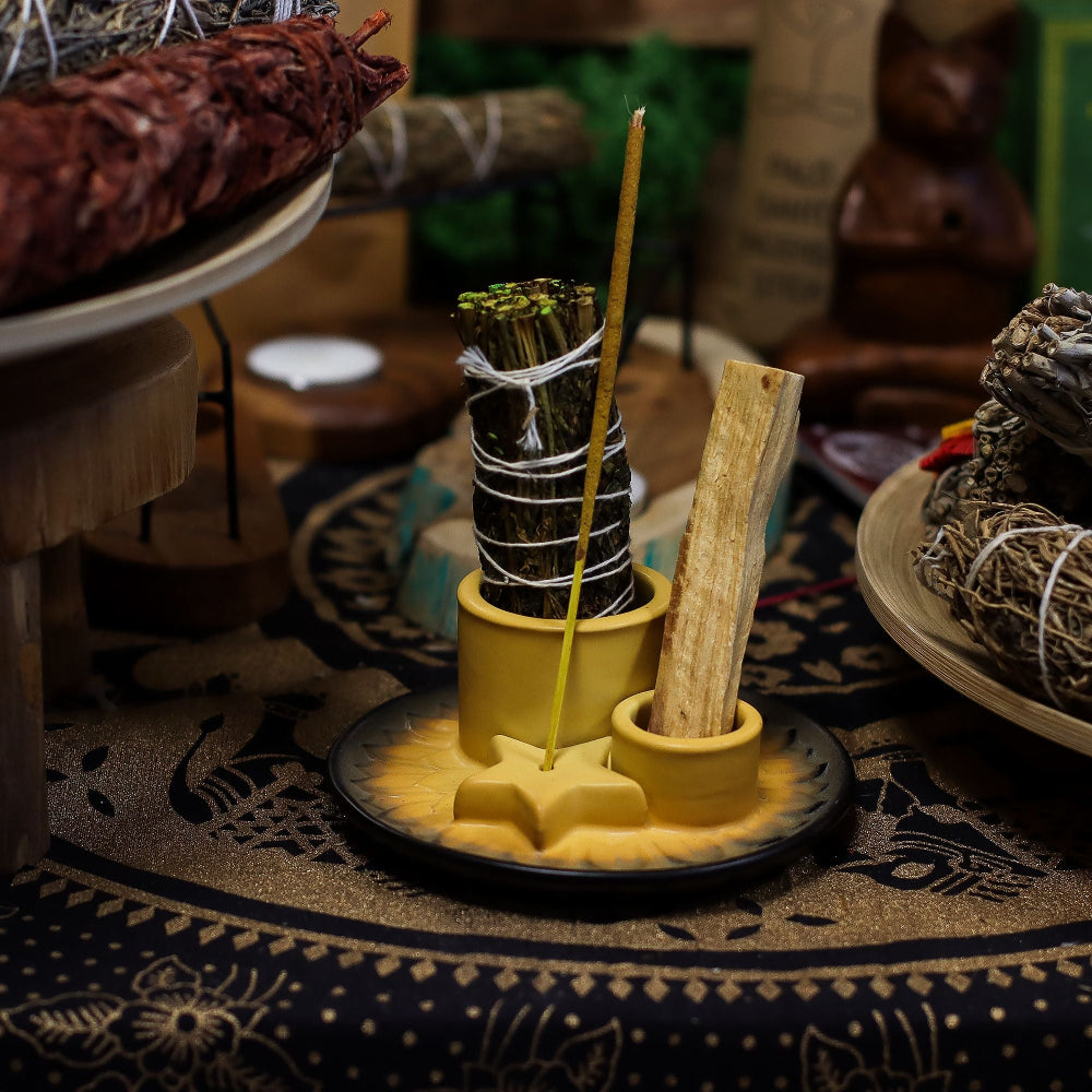 Yellow ceramic holder with sage and wooden stick on a patterned surface