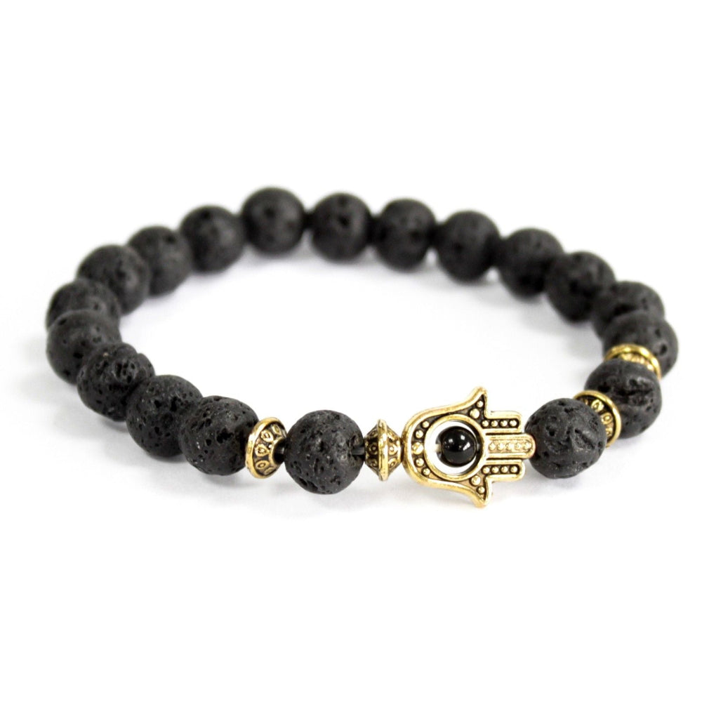 Black beaded bracelet with gold evil eye and Hamsa hand charm on a white background
