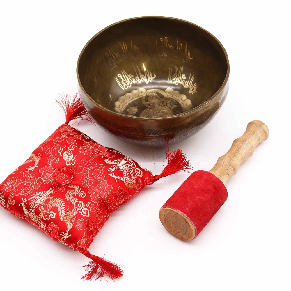 Tibetan singing bowl with red cushion and mallet on a white background