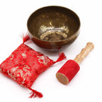 Tibetan singing bowl with red cushion and mallet on a white background