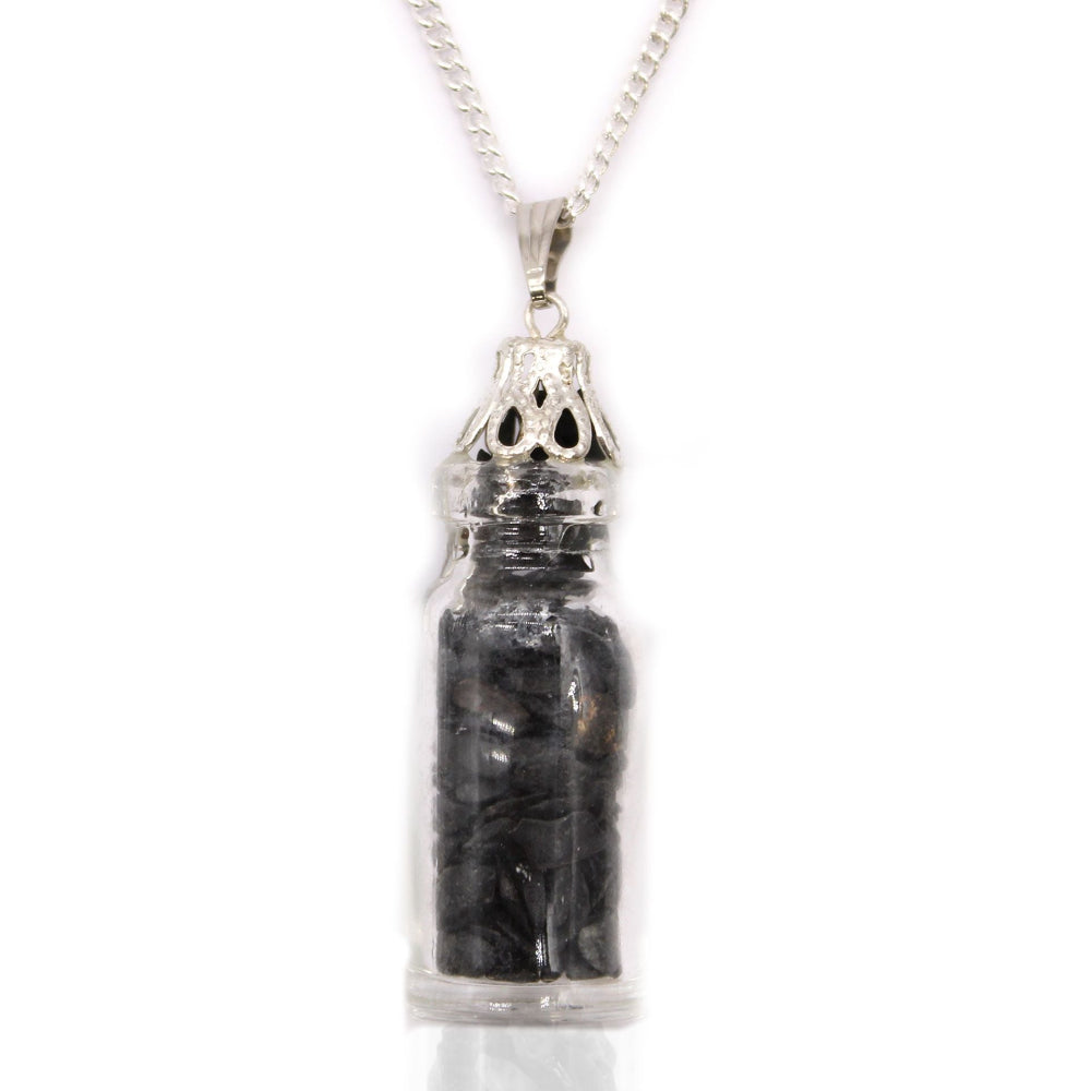 Silver pendant with a clear container holding black stones on a white background