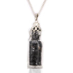 Silver pendant with a clear container holding black stones on a white background