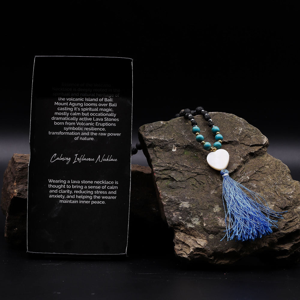 Necklace with blue tassel on a dark stone surface with descriptive text card.