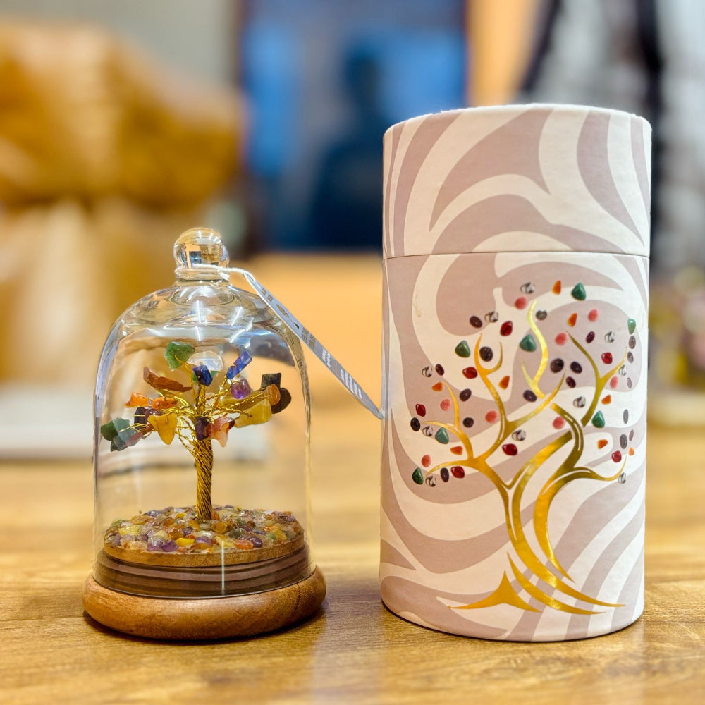 Decorative item with tree design inside a glass dome and on a cylindrical container with a tree pattern.