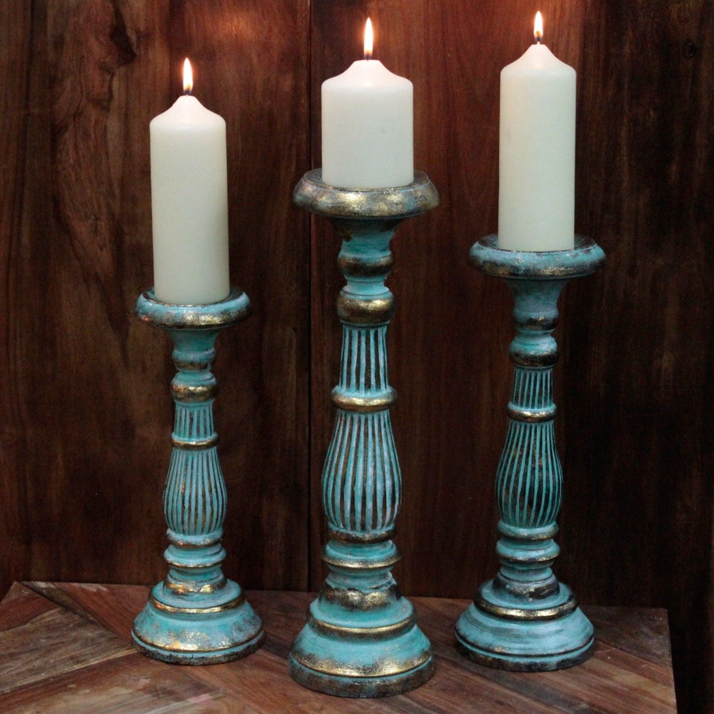 Three candle holders with candles on a wooden surface and dark wooden background