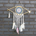 Dreamcatcher with feathers hanging on a brick wall