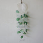 Decorative hanging with green and clear glass pieces on a white background