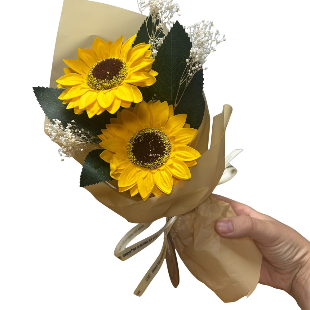 Bouquet of sunflowers wrapped in brown paper held by a hand on a white background