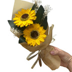 Bouquet of sunflowers wrapped in brown paper held by a hand on a white background