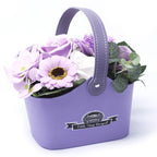 Purple flower arrangement in a matching basket with 'Petite Comp Bouquet' branding on a white background