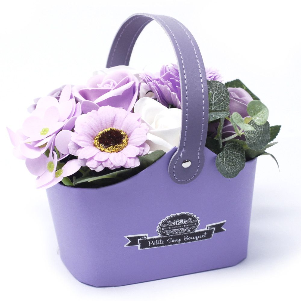 Purple flower arrangement in a matching basket with 'Petite Comp Bouquet' branding on a white background