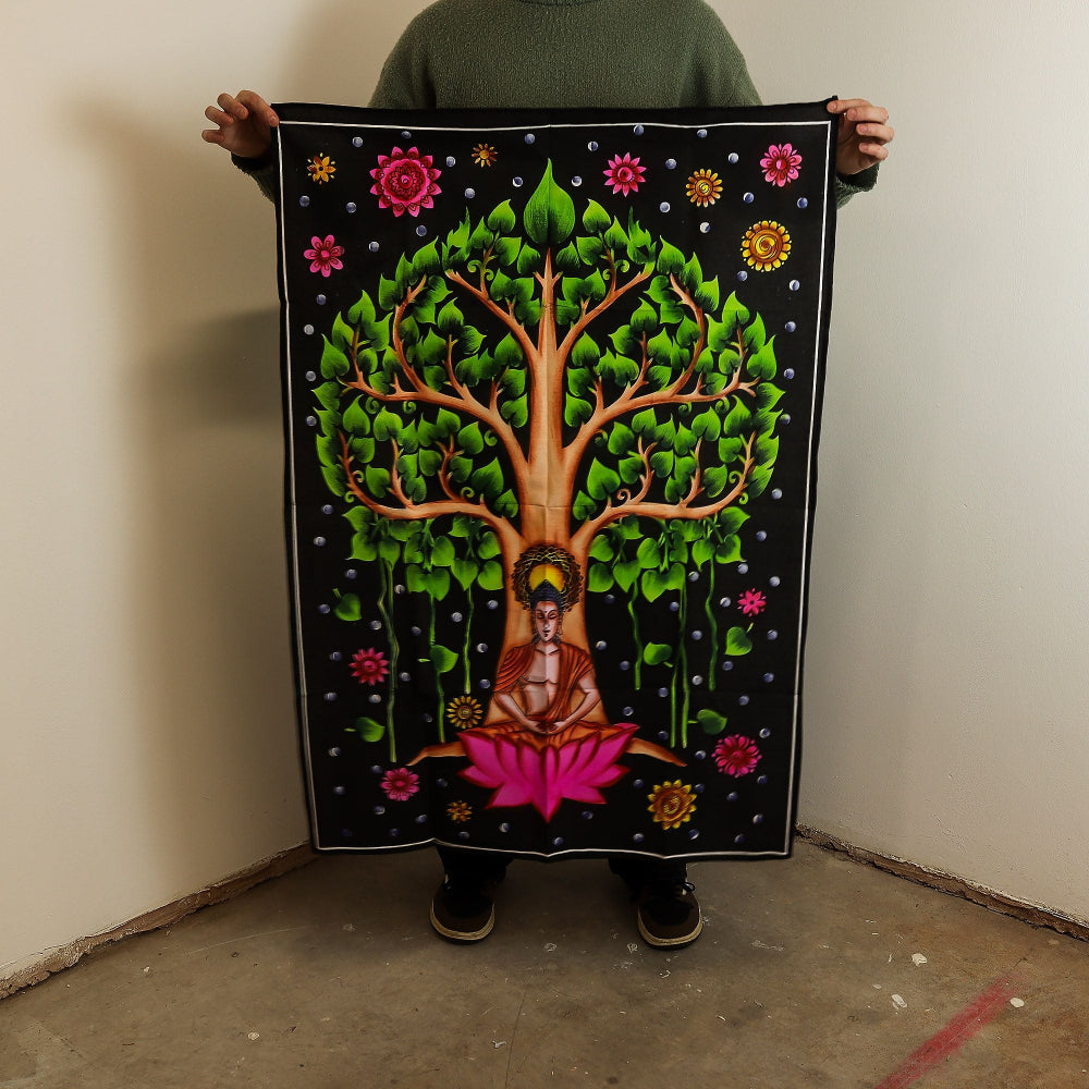 Person holding a colorful tapestry with a tree design and Buddha figure.
