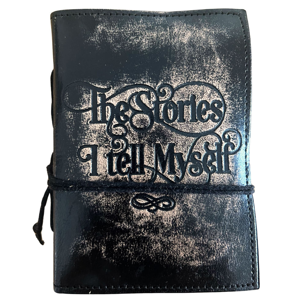 Black leather-bound notebook with 'The Stories I Tell Myself' text on a white background