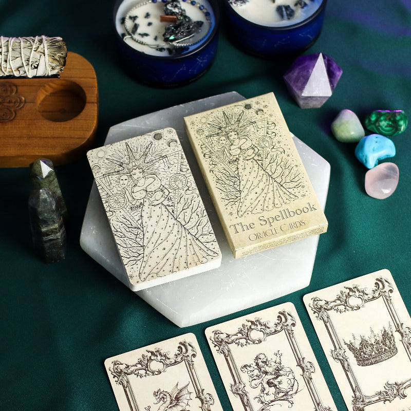 Witchcraft items including tarot cards, crystals, and a book titled 'The Spellbook' on a green surface.