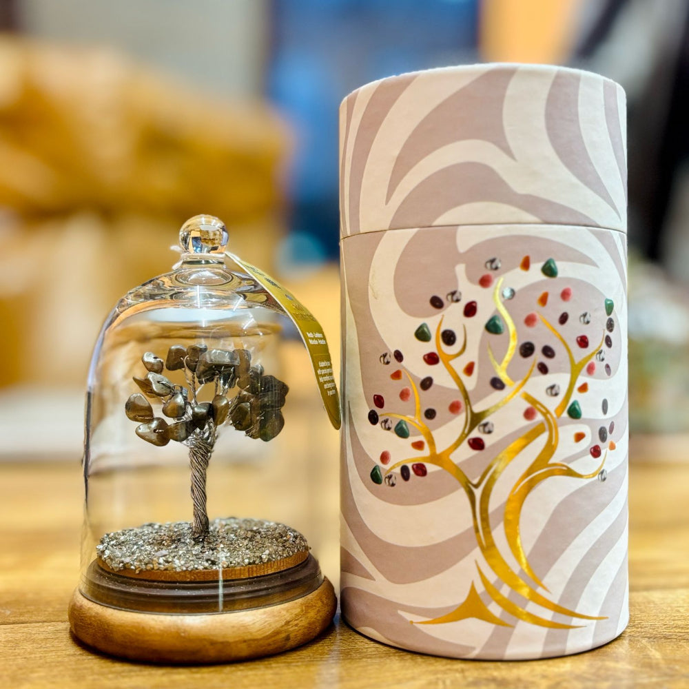 Decorative item with a tree inside a glass dome and a matching cylindrical container on a wooden surface.
