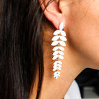 Close-up of a person wearing a white leaf-shaped earring.