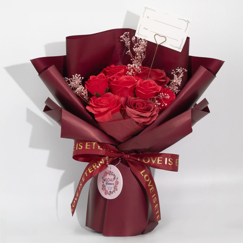 Bouquet of soap roses wrapped in burgundy paper with a decorative ribbon on a white background