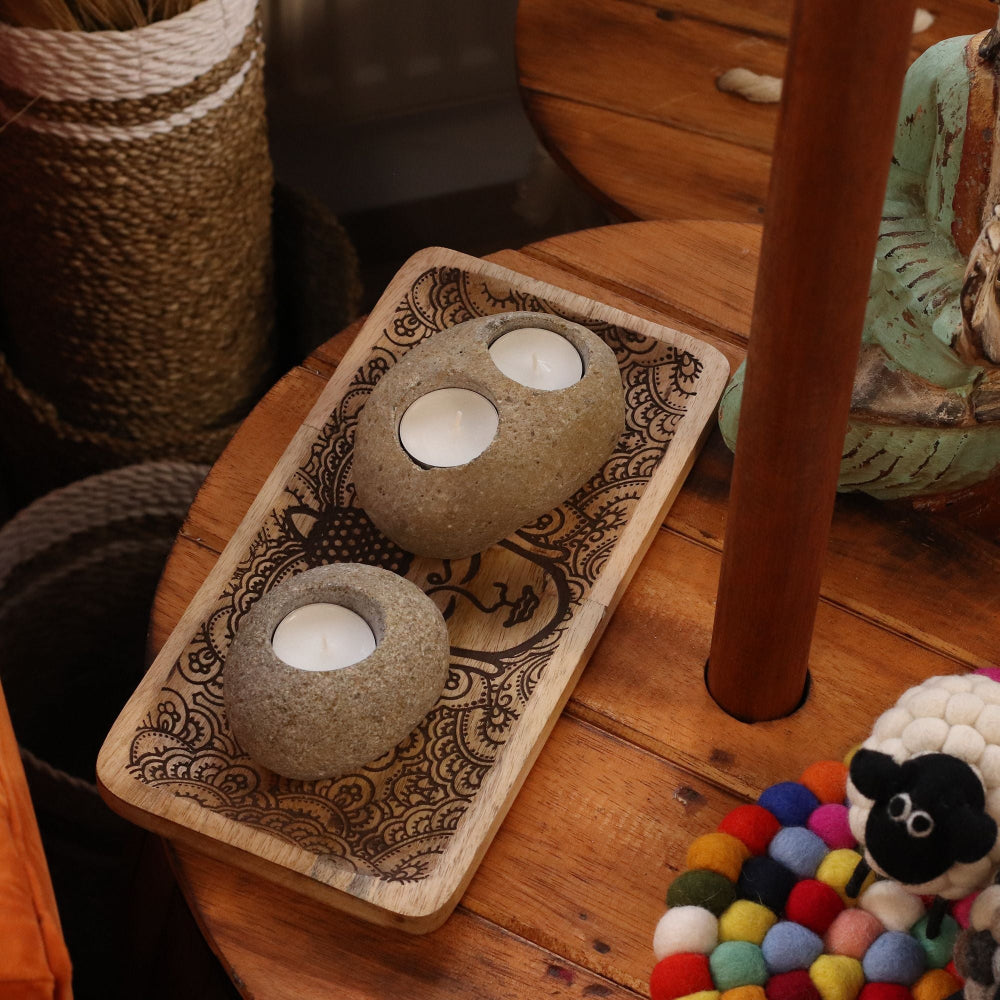 Decorative stone candle holders on a wooden tray with a rustic background