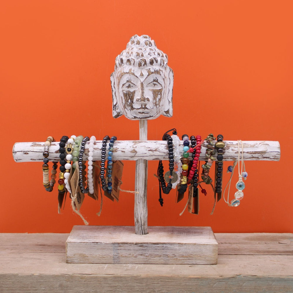 Jewelry holder with Buddha head design against an orange background