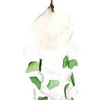 Decorative hanging with green and white glass pieces on a white background