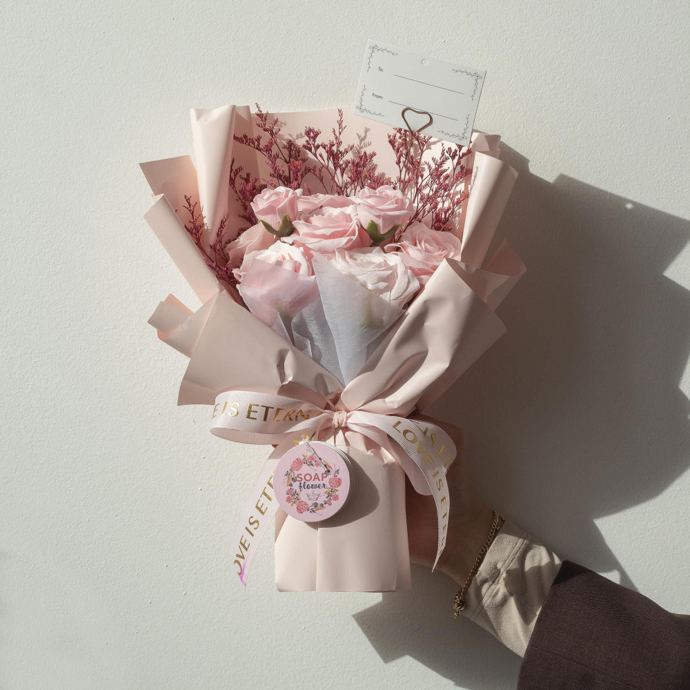 Bouquet of soap flowers wrapped in paper with a ribbon on a light gray background