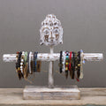 Wooden bracelet holder with Buddha head design displaying various bracelets on a gray background
