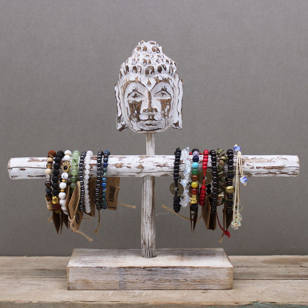 Wooden bracelet holder with Buddha head design displaying various bracelets on a gray background
